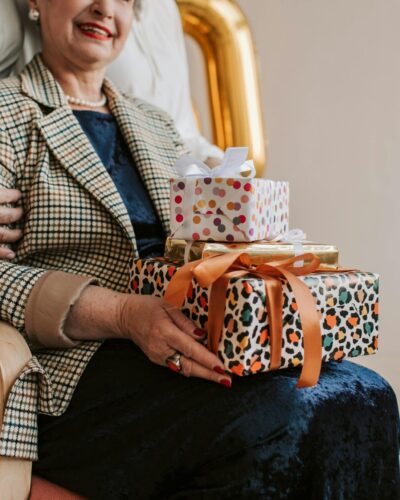 Une grand-mère souriante reçoit avec émotion des cadeaux lors de sa fête, entourée de l'affection de ses proches.